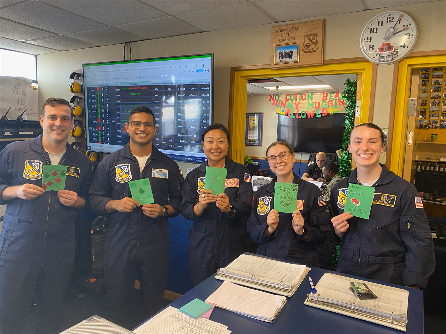 Members of the Blue Angles Squadron holding Christmas cards made by students.